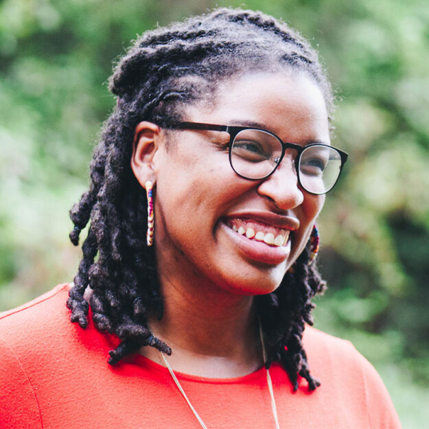 21_Healing-Transitions_EOY_Stories_Square_A-J_01 Young woman with braids and red shirt smiling
