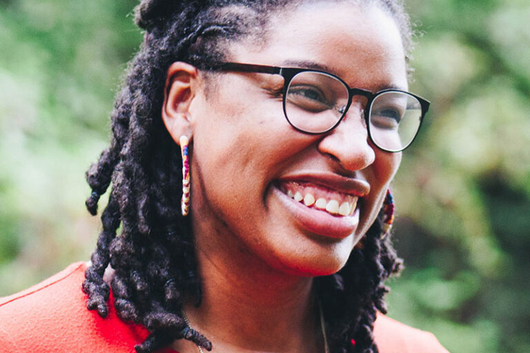 Young woman with braids and red shirt smiling