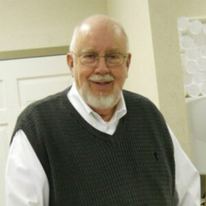 Fred Barber inside with white button down shirt and black sweater smiling