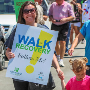 Middle age lady holding a "Walk for Recovery" sign